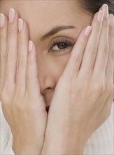 Close up of woman covering face with hands.