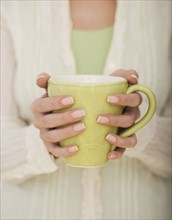 Close up of woman holding coffee mug.