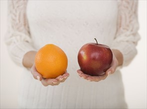 Close up of woman holding apple and orange.