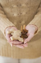 Close up of woman holding ginger root and spices.