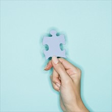 Woman holding jigsaw puzzle piece.