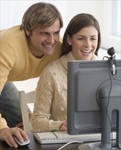 Couple smiling at webcam on computer.