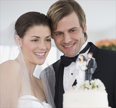 Bride and groom smiling at wedding cake.