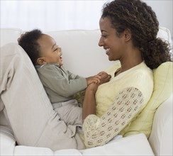 Mother and baby laughing on sofa.