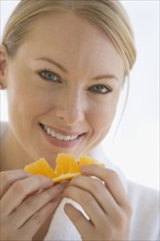 Woman eating orange wedge.