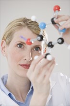 Female scientist looking at molecule model.