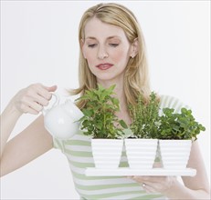 Woman watering herbs in pots.