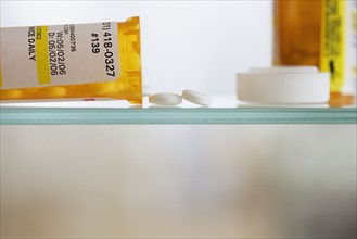 Medication bottle and pills on shelf.