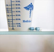 Medication and cup on shelf.