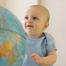 Baby looking at globe.