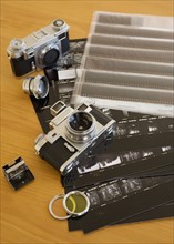 Cameras, negatives and contact sheets on table.