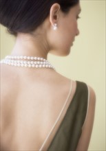 Rear view of woman wearing pearl necklace.