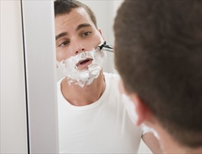 Man shaving in mirror.