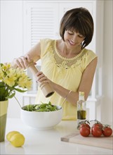 Woman grinding pepper onto salad.