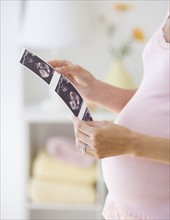 Pregnant woman looking at ultrasound printout.
