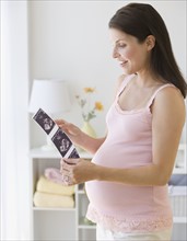 Pregnant woman looking at ultrasound printout.