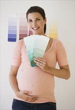 Pregnant woman looking at paint swatches.