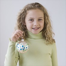 Girl holding Christmas ornament.