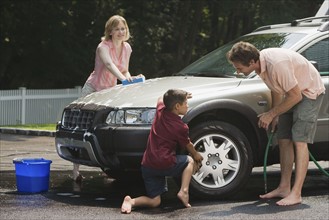 Family washing car in driveway.