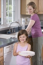 Mother and daughter washing dishes.