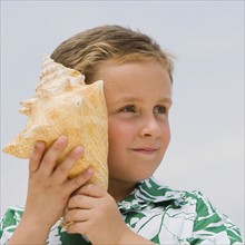Boy listening to conch seashell.