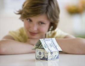 Woman looking at model house made of US dollars.