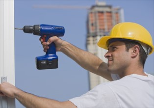 Construction worker using cordless drill.