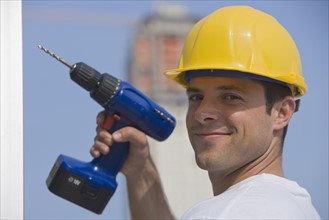 Construction worker holding cordless drill.