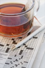 Close up of crossword puzzle and tea.