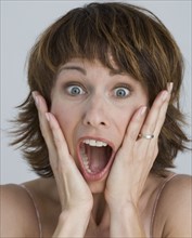 Woman looking surprised with hands on cheeks.