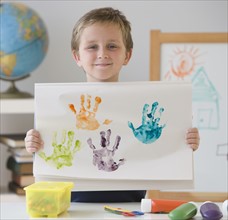 Boy holding handprint painting.