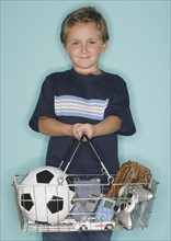 Boy holding shopping basket with toys.