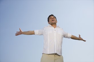 Low angle view of man with arms outstretched.