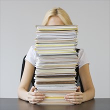 Businesswoman behind stack of paperwork.