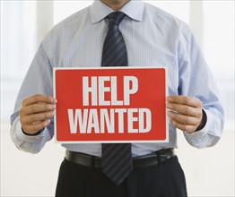 Businessman holding Help Wanted sign.