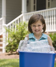 Girl carrying recycling bin.