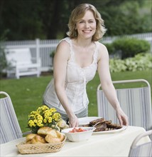Woman setting table outdoors.