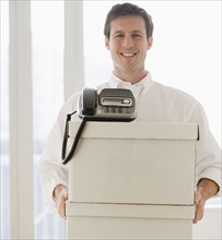 Businessman carrying telephone and storage boxes.