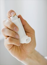 Person holding asthma inhaler.