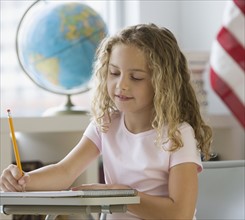 Girl writing at school desk.