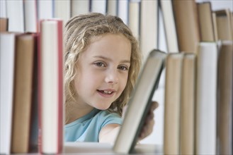 Girl looking at books on shelf.