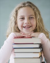 Girl leaning on stack of books.