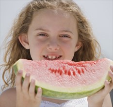 Girl eating slice of watermelon.