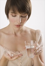 Woman taking pills with glass of water.