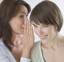 Woman telling secret to friend.