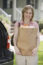 Woman holding bag of groceries.