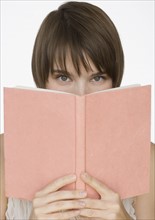 Woman holding open book over face.