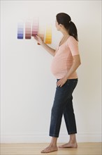Pregnant woman looking at paint swatches.
