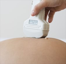 Ultrasound wand on pregnant woman .
