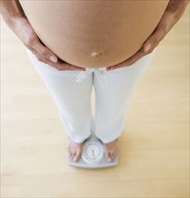Pregnant woman standing on scale.